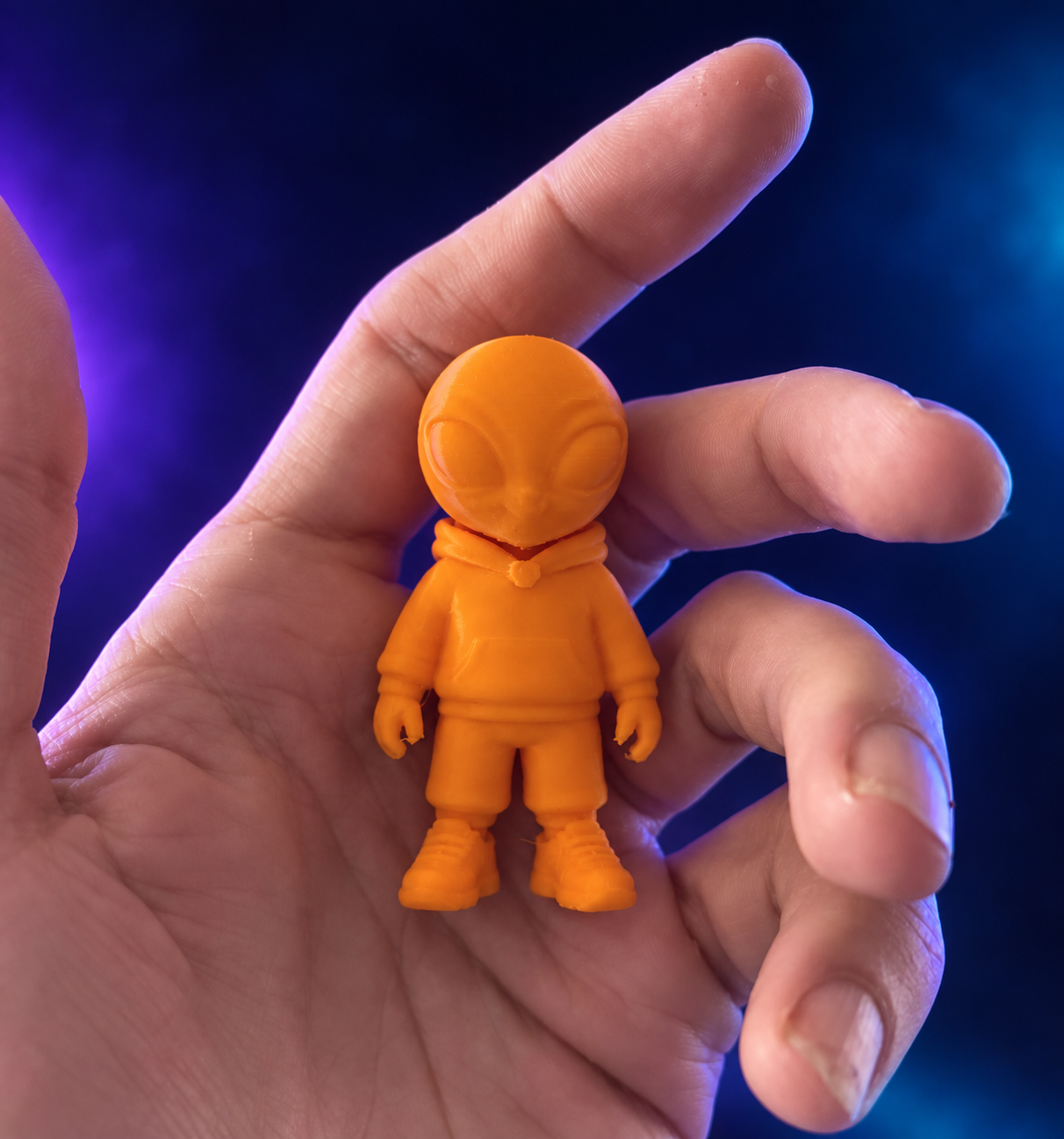 Actual orange Monnie Mini held in a hand to show his approximately three-inch size